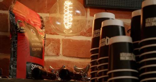 A stack of coffee cups underneath a vintage light bulb