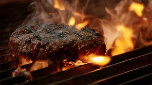 A burger being cooked on a flaming grill