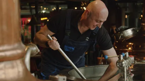 Man mixing a vat of beer